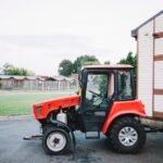 A vintage 70537865 Allis-Chalmers tractor in a rural farm setting with green fields and a blue sky.