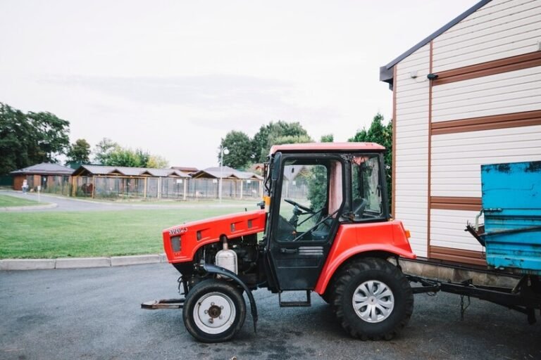 A vintage 70537865 Allis-Chalmers tractor in a rural farm setting with green fields and a blue sky.